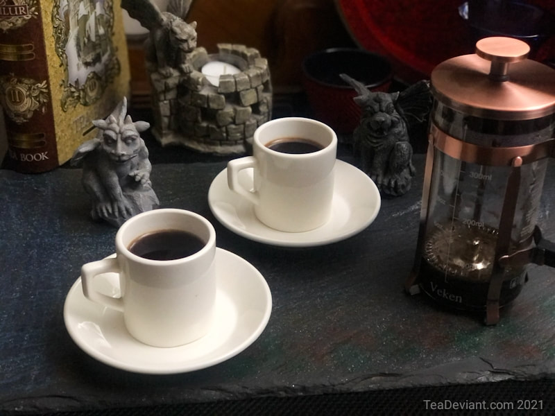 Image of french press coffee maker cups and gargoyle statues